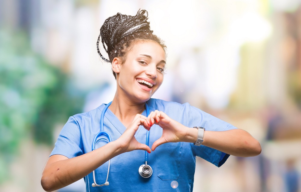 young braided hair african american girl professional surgeon over isolated background smiling in love showing heart symbol and shape with hands. romantic concept.